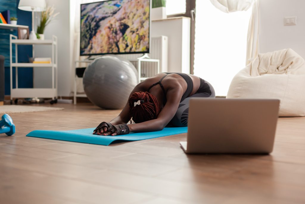 black-woman-sitting-yoga-mate-doing-stretching-relaxing